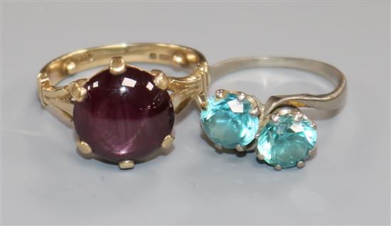 An 18ct white gold and blue zircon two-stone cross-over ring and a 9ct yellow gold ring set with a purple cabochon star sapphire.